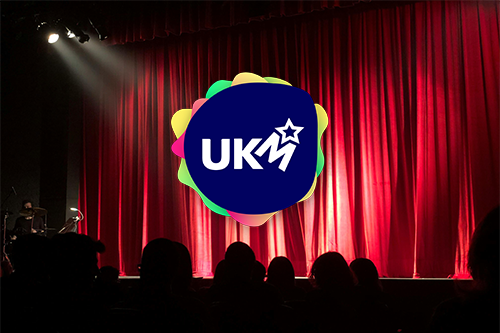 Bilde av en scene med sceneteppe og UKM-logo i front.