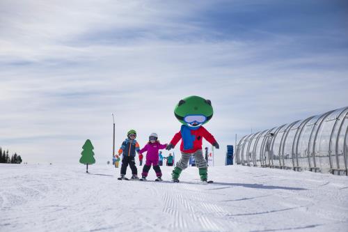 Maskott i Hafjell står på ski med barn.