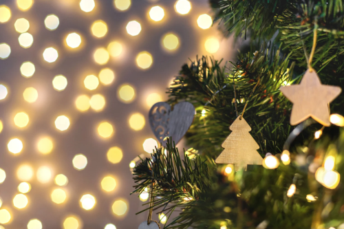 Bilde av pyntet julegran med julelys i bakgrunnen.